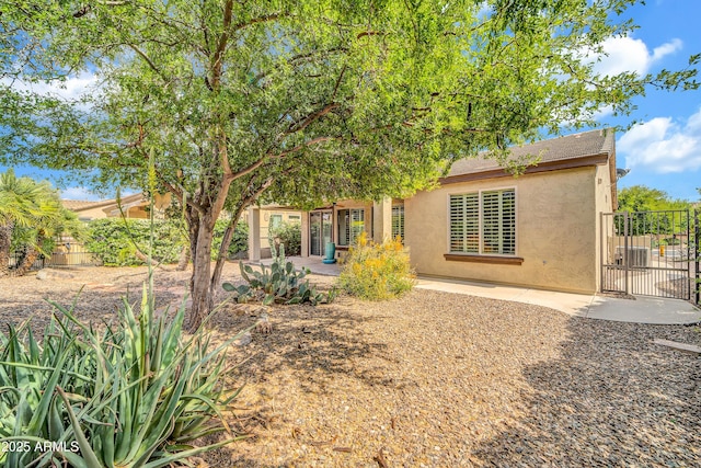 rear view of property featuring a patio area, a gate, stucco siding, and fence