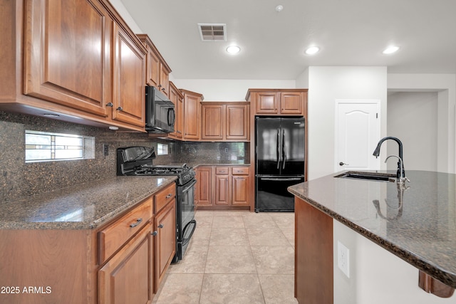 kitchen with backsplash, a sink, visible vents, black appliances, and brown cabinetry