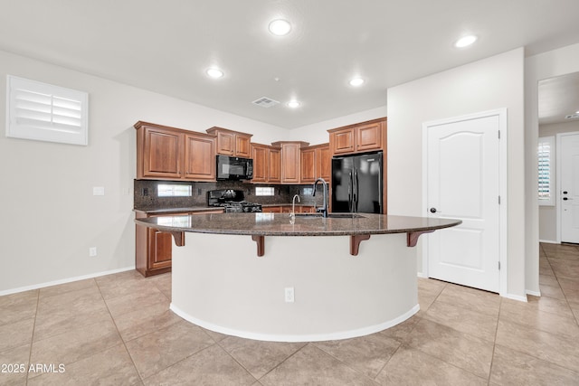 kitchen with a kitchen bar, a sink, black appliances, and brown cabinets