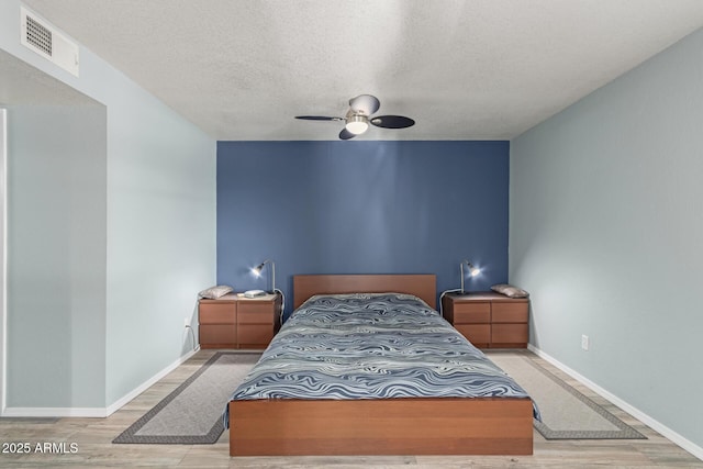 bedroom featuring a textured ceiling, light hardwood / wood-style floors, and ceiling fan