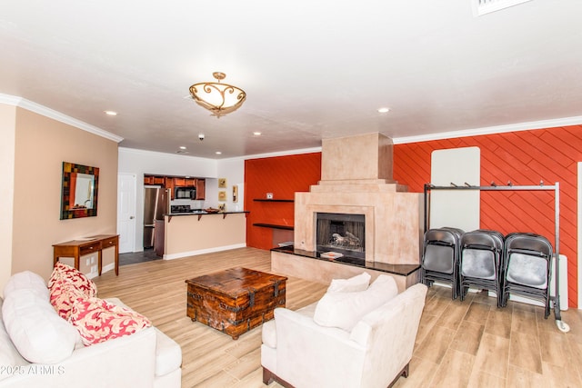 living room featuring crown molding, light hardwood / wood-style flooring, a fireplace, and wood walls