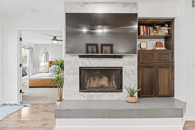 living room featuring a high end fireplace, light wood-type flooring, and ceiling fan