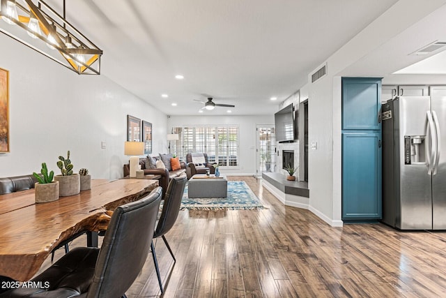 dining room featuring a large fireplace, ceiling fan, and hardwood / wood-style floors