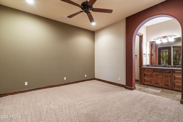 3523 E Presidio Cir, Mesa, AZ 85213 - empty room featuring light carpet, arched walkways, ceiling fan, a sink, and baseboards