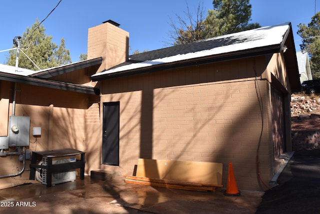 view of home's exterior with brick siding, a chimney, and a patio