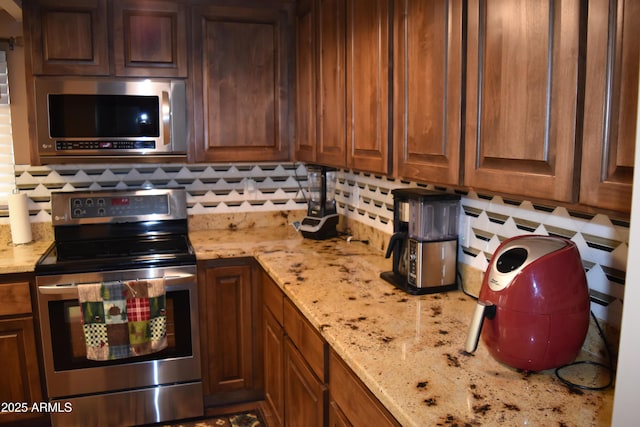 kitchen with light stone countertops, tasteful backsplash, and appliances with stainless steel finishes