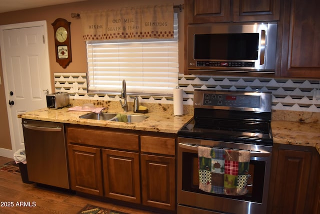 kitchen featuring a sink, stainless steel appliances, light stone countertops, and decorative backsplash