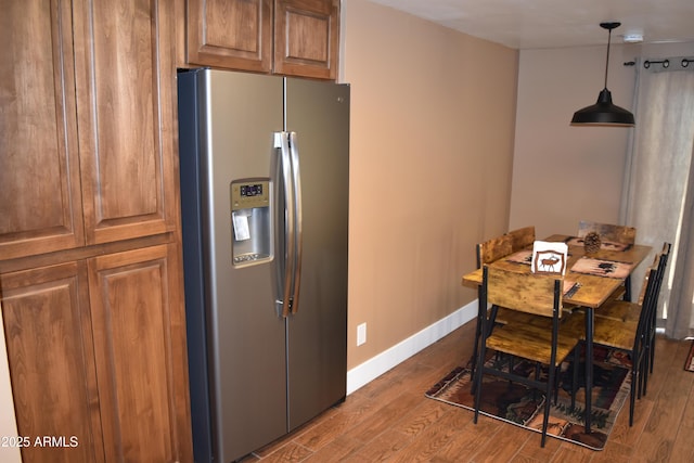 kitchen featuring brown cabinets, dark wood-type flooring, pendant lighting, stainless steel fridge, and baseboards