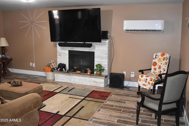 living area with a stone fireplace, baseboards, a wall mounted air conditioner, and wood tiled floor