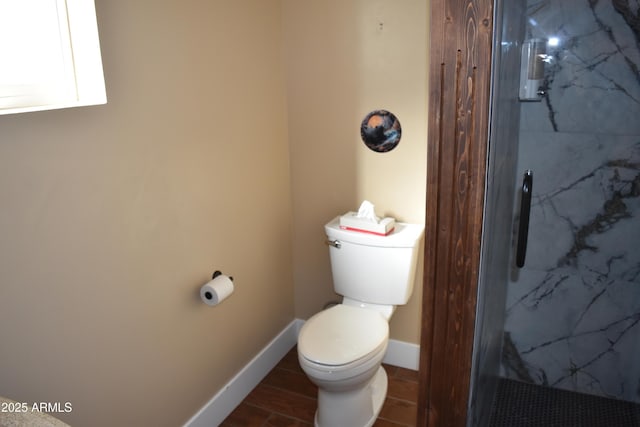 bathroom with toilet, wood finished floors, baseboards, and a marble finish shower