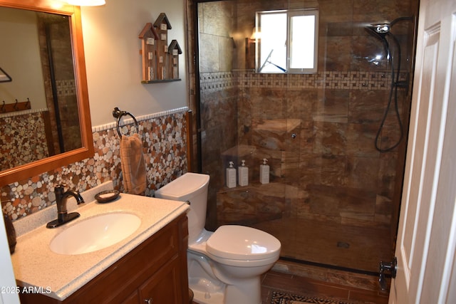 bathroom with vanity, tile walls, toilet, and a tile shower