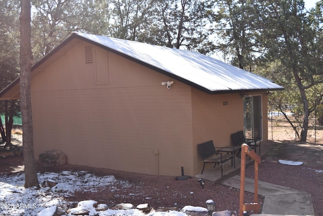 view of snowy exterior with metal roof, an outbuilding, and concrete block siding