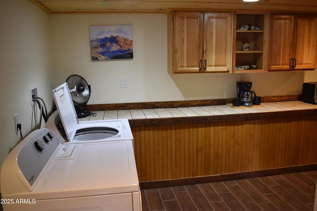 washroom featuring dark wood finished floors, cabinet space, and independent washer and dryer