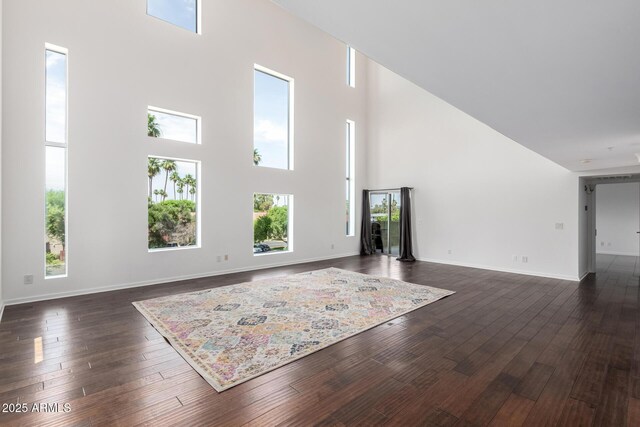 1111 W University Dr Unit 3016, Tempe, AZ 85281 - unfurnished living room with a towering ceiling, healthy amount of natural light, dark wood finished floors, and baseboards