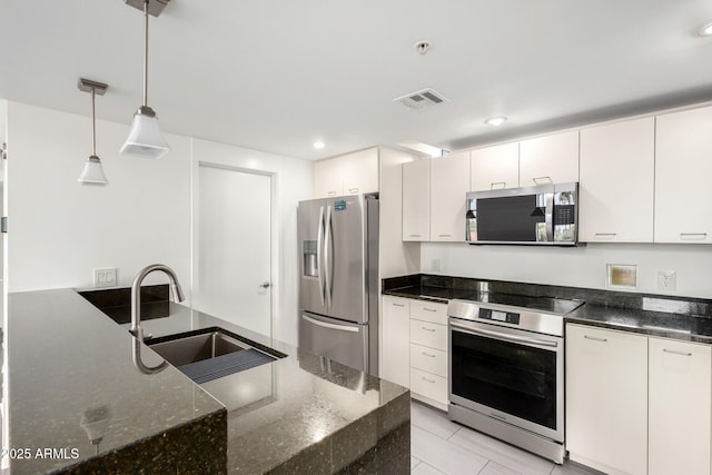 1111 W University Dr Unit 3016, Tempe, AZ 85281 - kitchen featuring appliances with stainless steel finishes, a sink, dark stone counters, decorative light fixtures, and white cabinets