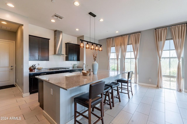 12035 W Roy Rogers Rd, Peoria, AZ 85383 - kitchen featuring pendant lighting, an island with sink, a kitchen breakfast bar, light stone counters, and wall chimney exhaust hood