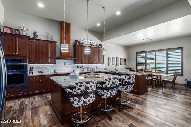 kitchen featuring a breakfast bar, a center island, light stone counters, and dark hardwood / wood-style flooring