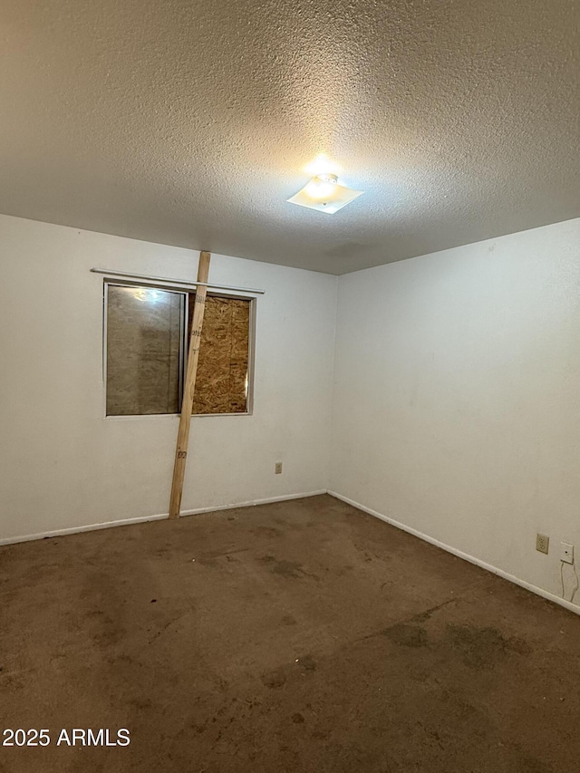carpeted empty room with baseboards and a textured ceiling