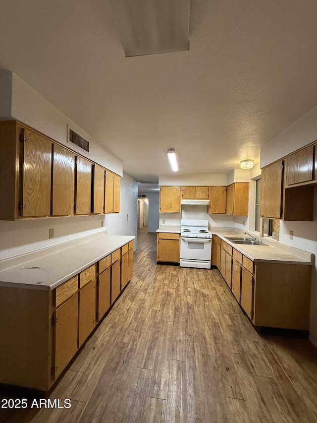 kitchen with visible vents, brown cabinetry, electric range, wood finished floors, and a sink