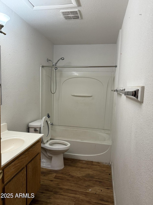 bathroom with vanity, toilet, tub / shower combination, wood finished floors, and visible vents