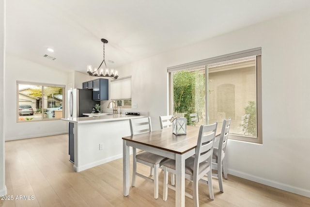 dining space with a chandelier, visible vents, baseboards, vaulted ceiling, and light wood-type flooring