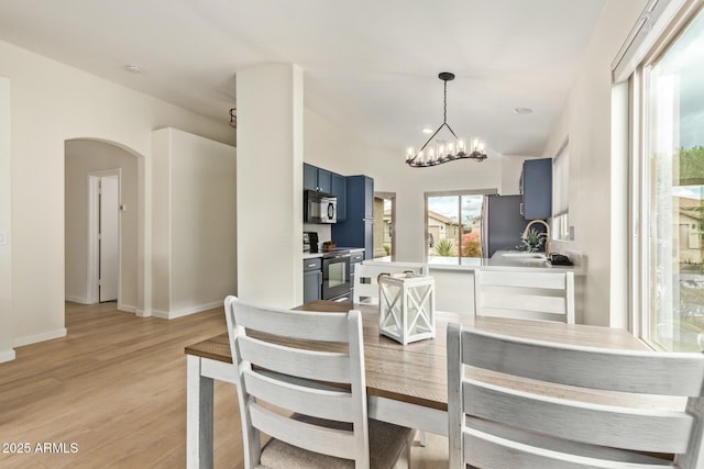 dining room featuring an inviting chandelier, light wood-style flooring, arched walkways, and baseboards