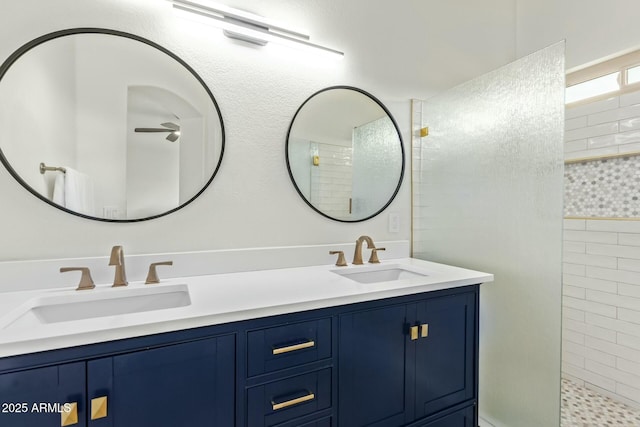 bathroom featuring double vanity, a tile shower, and a sink