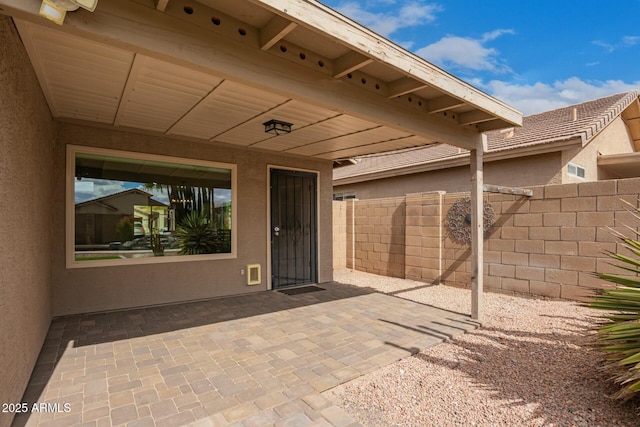 doorway to property with a patio area, fence, and stucco siding