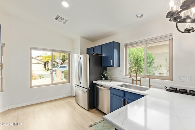 kitchen with visible vents, appliances with stainless steel finishes, blue cabinets, vaulted ceiling, and a sink