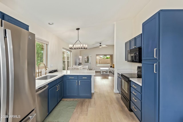 kitchen with a sink, blue cabinets, light wood-type flooring, a peninsula, and black appliances