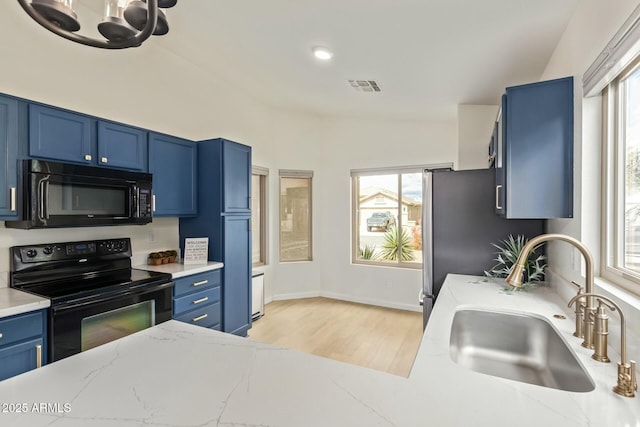 kitchen with blue cabinets, black appliances, visible vents, and a sink