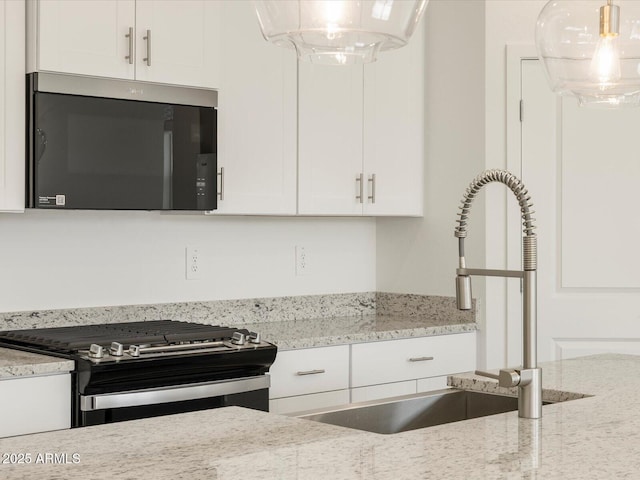 kitchen with light stone countertops, stainless steel gas range oven, and white cabinetry