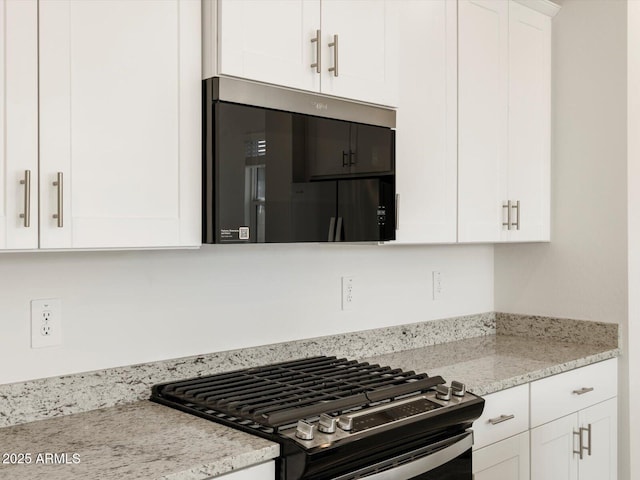 kitchen with range with gas stovetop, white cabinetry, and light stone counters