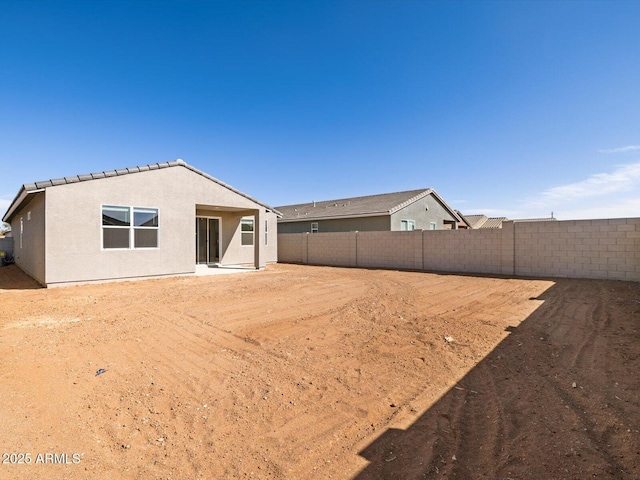 rear view of property with a fenced backyard and stucco siding