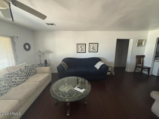 living room featuring ceiling fan and dark hardwood / wood-style floors