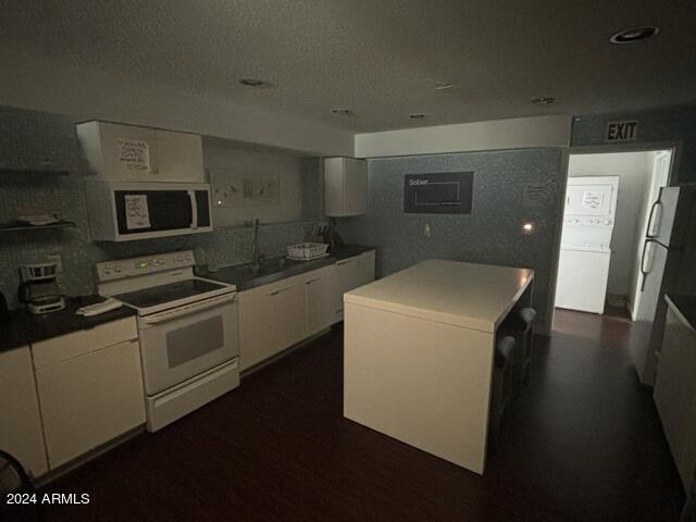 kitchen featuring fridge, white range with electric stovetop, a textured ceiling, a kitchen island, and white cabinets