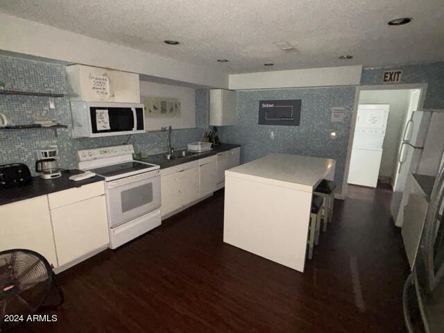 kitchen with sink, white appliances, white cabinetry, dark hardwood / wood-style floors, and a center island