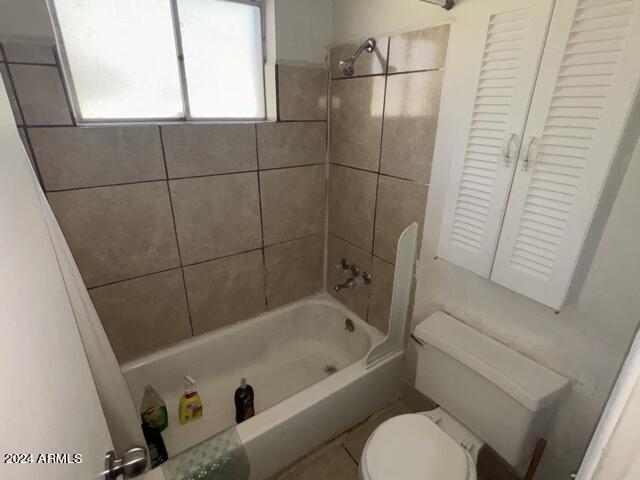 bathroom featuring tiled shower / bath combo and toilet