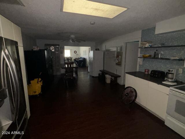 kitchen with dark hardwood / wood-style floors, white cabinets, white appliances, ceiling fan, and a textured ceiling