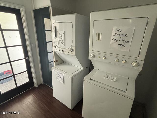 clothes washing area featuring stacked washer and clothes dryer and dark hardwood / wood-style floors