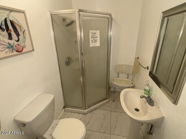 full bathroom featuring marble finish floor, a sink, a shower stall, and toilet