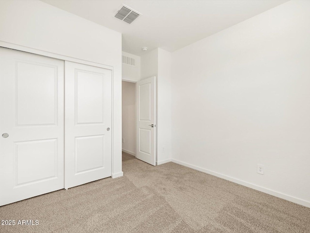 unfurnished bedroom with baseboards, a closet, visible vents, and light colored carpet