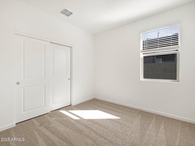 unfurnished bedroom with a closet, carpet flooring, visible vents, and baseboards