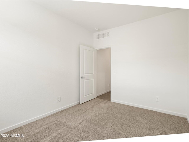 spare room featuring carpet floors, visible vents, and baseboards