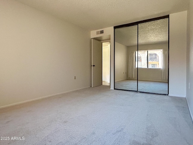 unfurnished bedroom featuring a closet, a textured ceiling, and carpet flooring