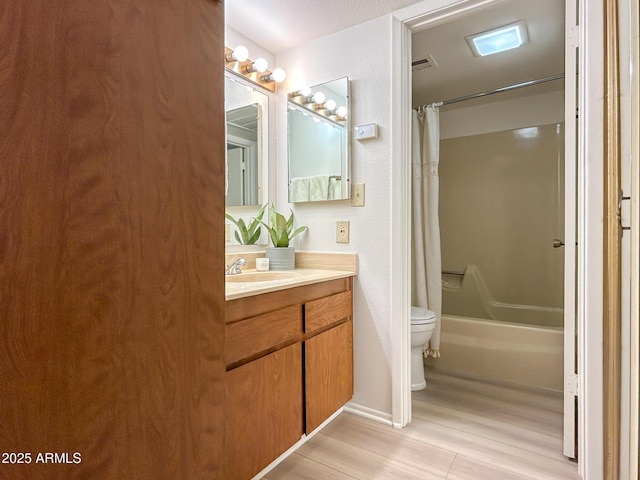 full bathroom with hardwood / wood-style flooring, vanity, shower / tub combo with curtain, and toilet