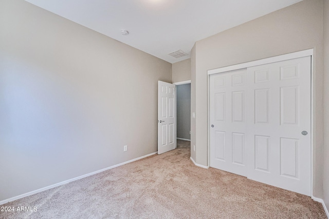 unfurnished bedroom with a closet and light carpet