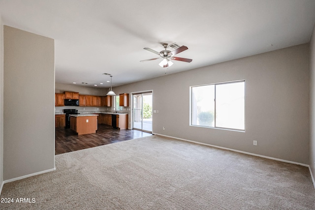 unfurnished living room with dark carpet and ceiling fan