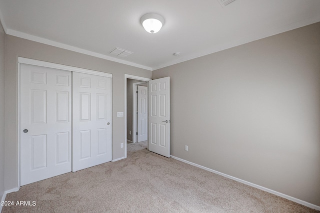 unfurnished bedroom featuring light colored carpet, ornamental molding, and a closet