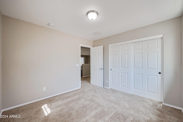 unfurnished bedroom with light colored carpet and a closet